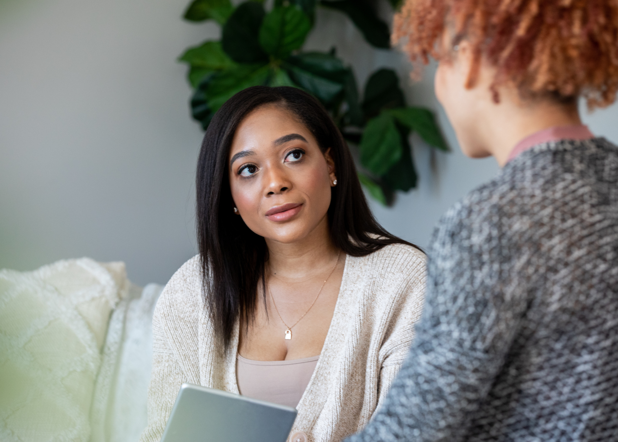 LCSW therapist and client sitting together in a gray room with a plant in background.