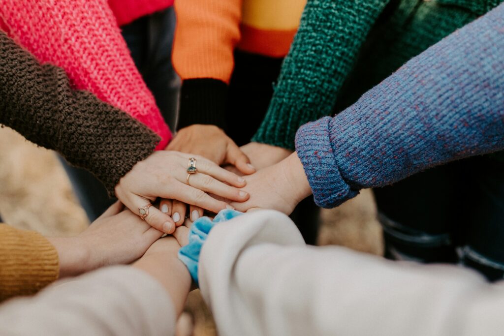 Group of people's hands together in a huddle after discussing managing political stress to avoid burnout.