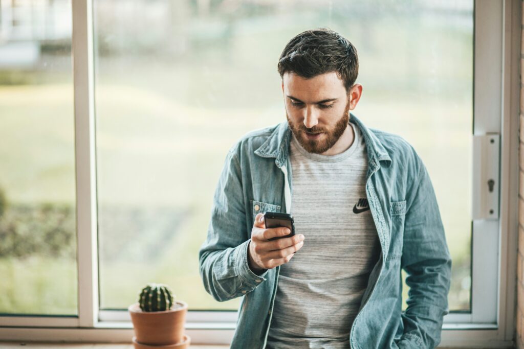 Man looking at his phone thinking about how to manage political stress and not burnout.