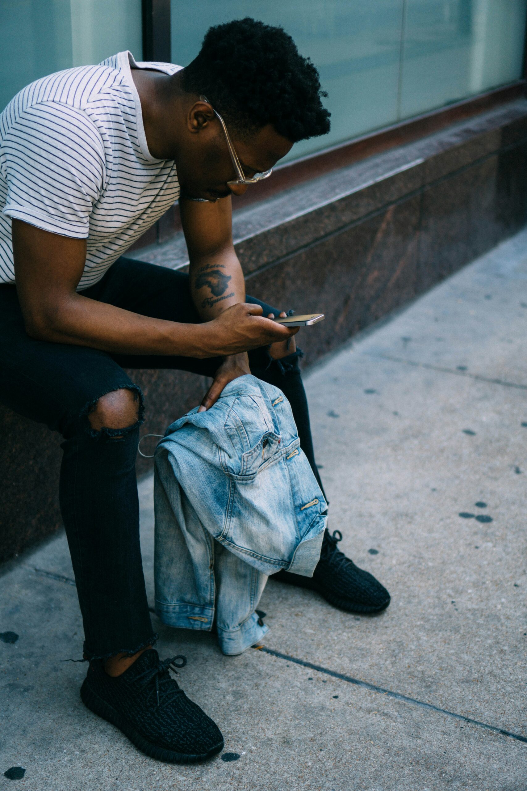 Man sitting outside looking at the news on his phone and thinking about how to manage political stress without checking out or burning out.