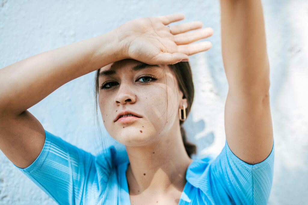 Woman shielding her face from the sun while dealing with SSRIs heat intolerance.