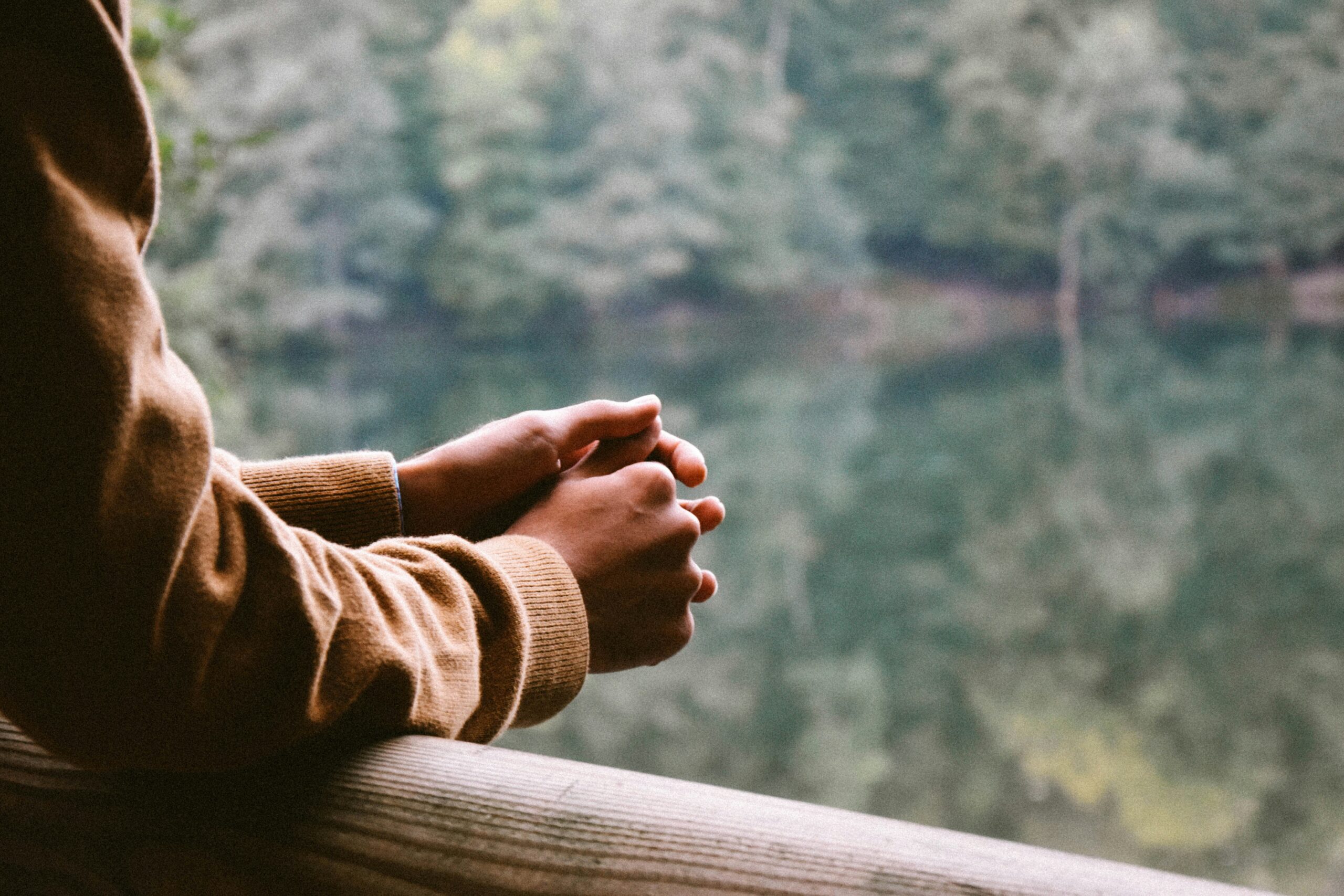 Close up of a person's arms resting on a railing overlooking a lake outside a New York therapy office that offers DBT skills groups.